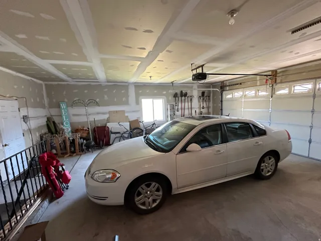 Two-car garage featuring concrete flooring, unpainted drywall, and a window for natural light