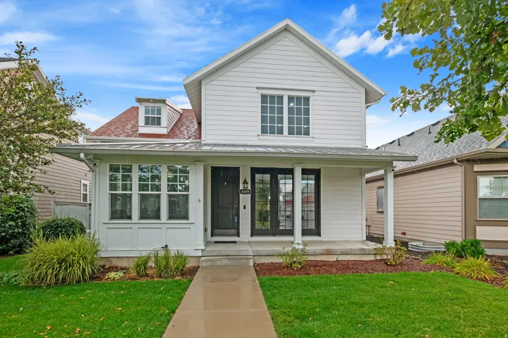 White siding exterior with a front porch, dormer window, and dark entry doors