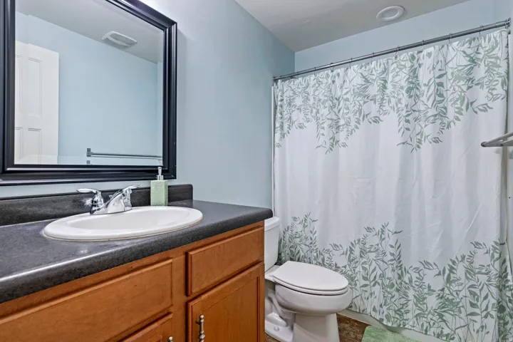 Bathroom featuring a vanity with a dark countertop, an oval undermount sink, and wood-finish cabinetry