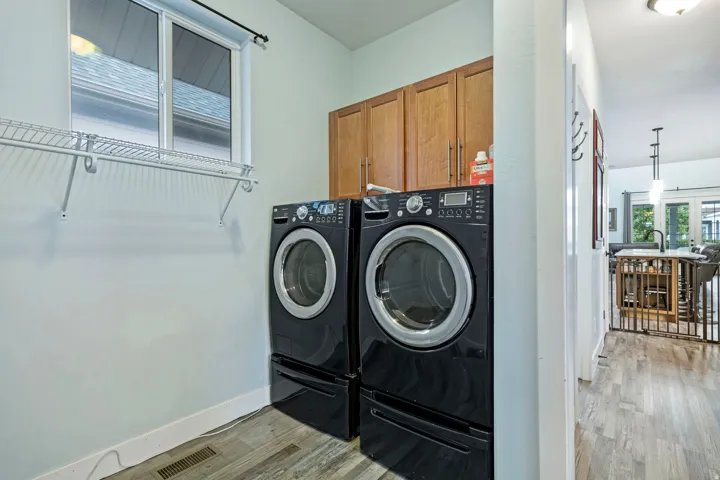 Dedicated laundry area featuring wood-finish cabinetry, a window with natural light, and wire shelving