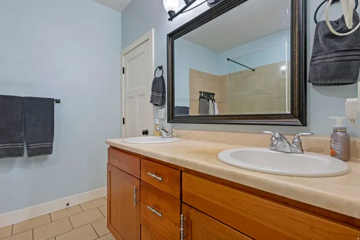 Dual vanity with wood-finish cabinetry, integrated sinks, and polished chrome faucets