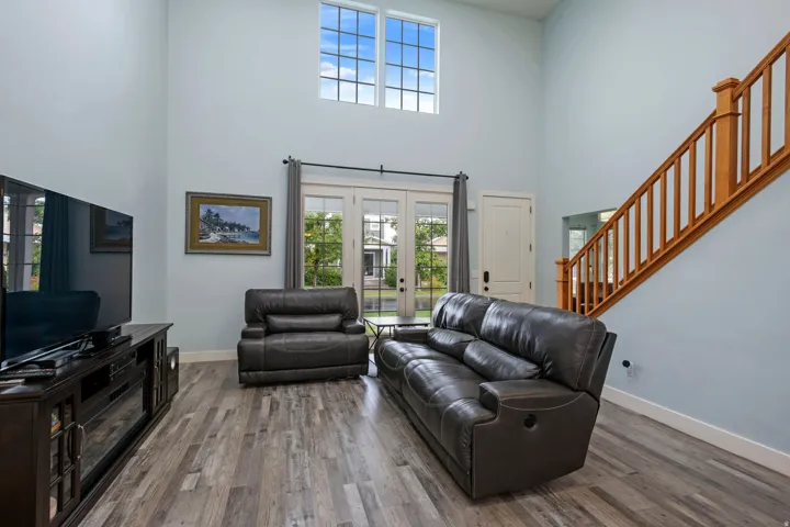 Two-story living area featuring wood-finish flooring, a prominent wooden staircase with balusters, and a large upper-level window