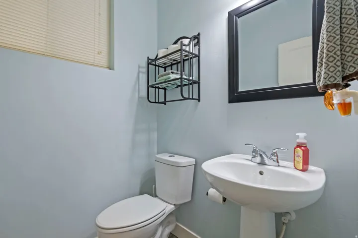 Pedestal sink with chrome faucet, framed mirror, and toilet