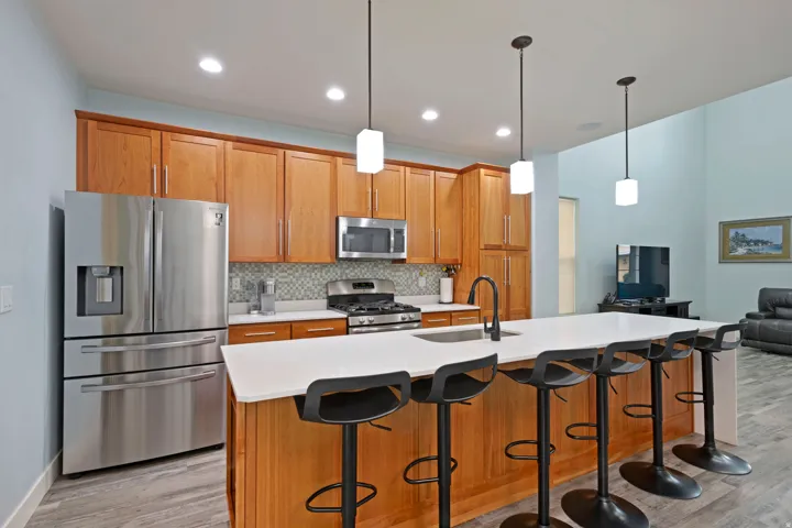 Kitchen featuring wood cabinetry, stainless steel appliances, white countertops, and a tiled backsplash