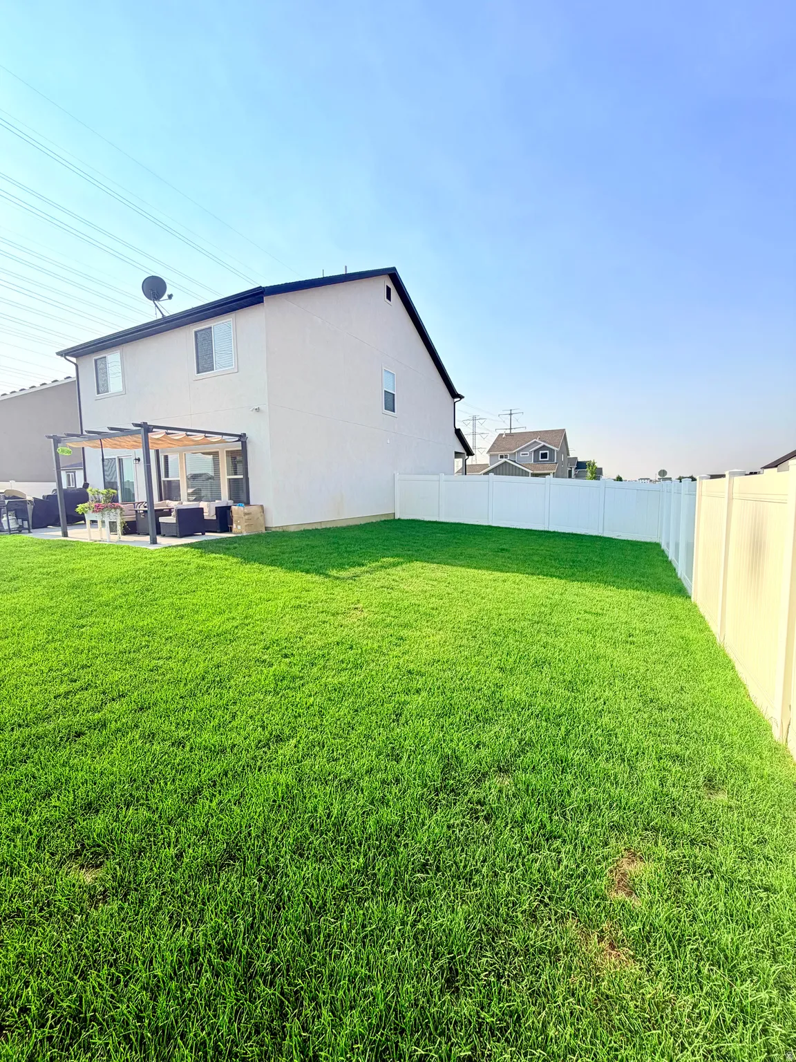 Expansive lawn area with a white privacy fence