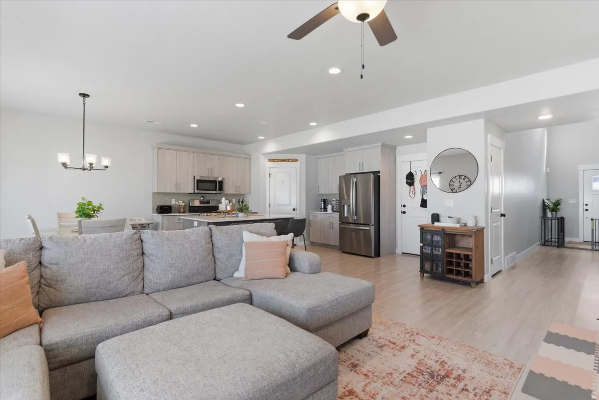 Open-concept living area with wood-finish flooring, recessed lighting, and a ceiling fan