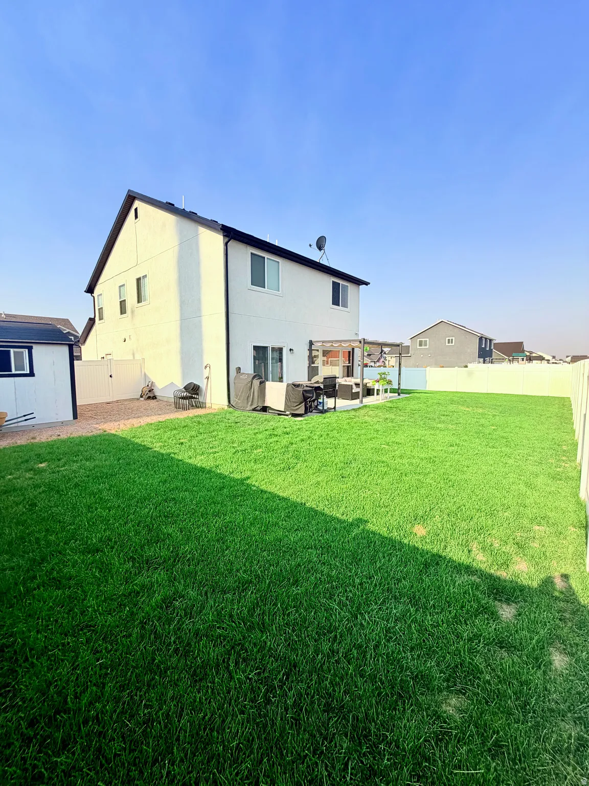 Expansive green lawn with a white privacy fence