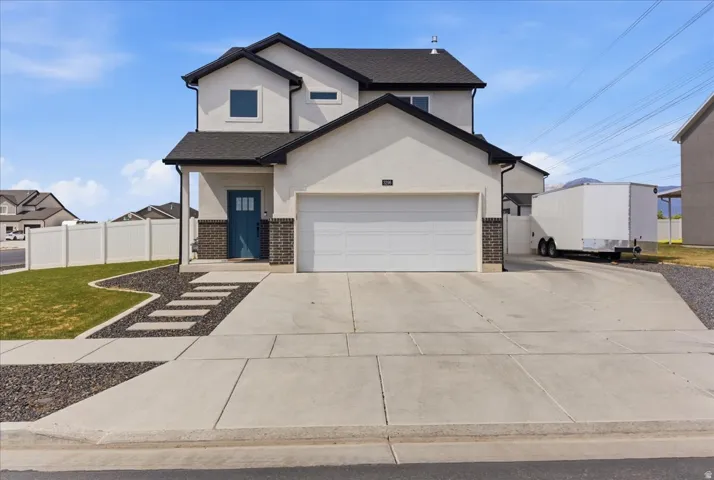 Contemporary two-story residence featuring a two-car garage, concrete driveway, and a welcoming porch with a blue entry door
