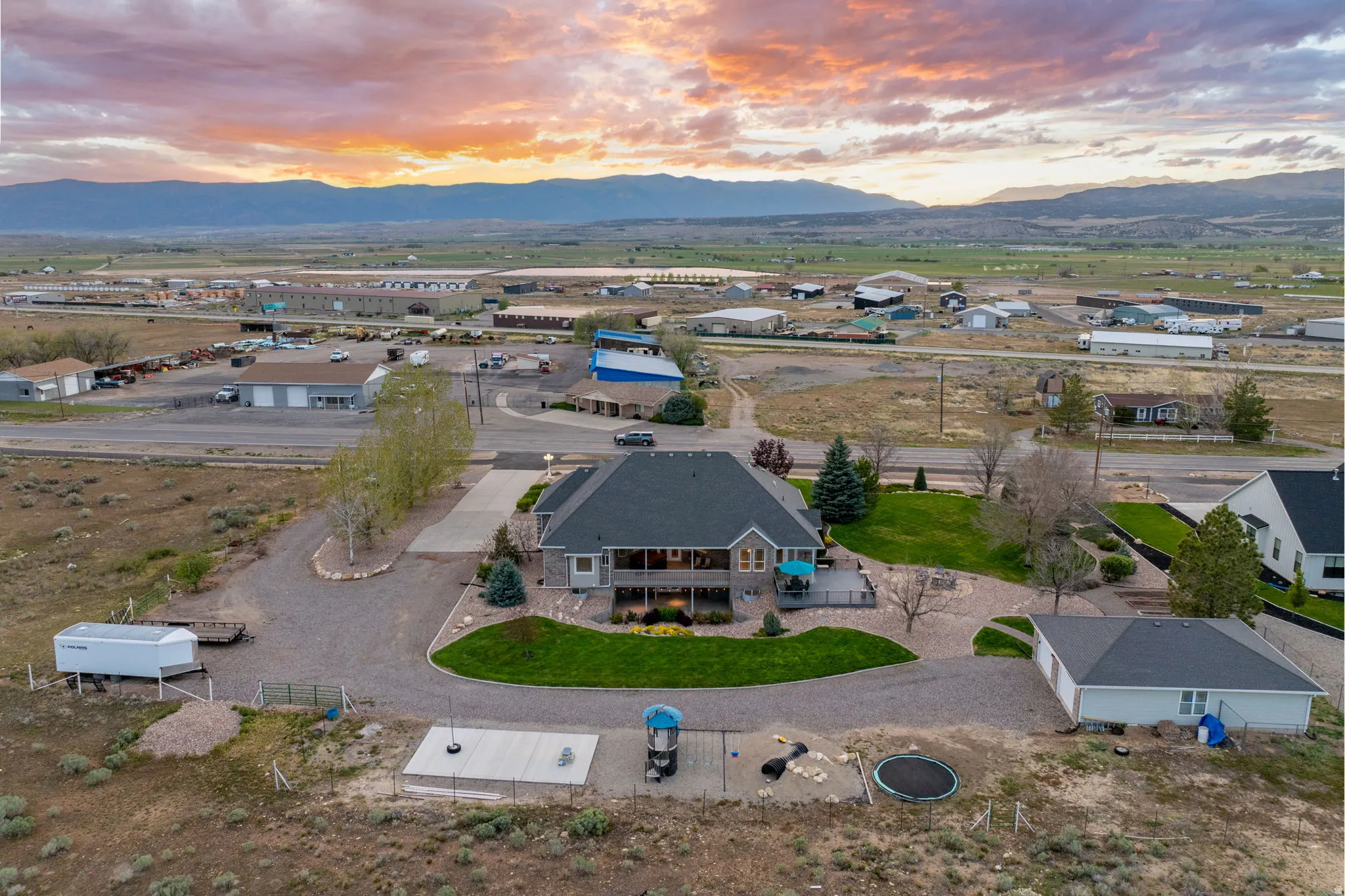Expansive property featuring a multi-level residence with a covered deck, a detached garage, and a large gravel driveway