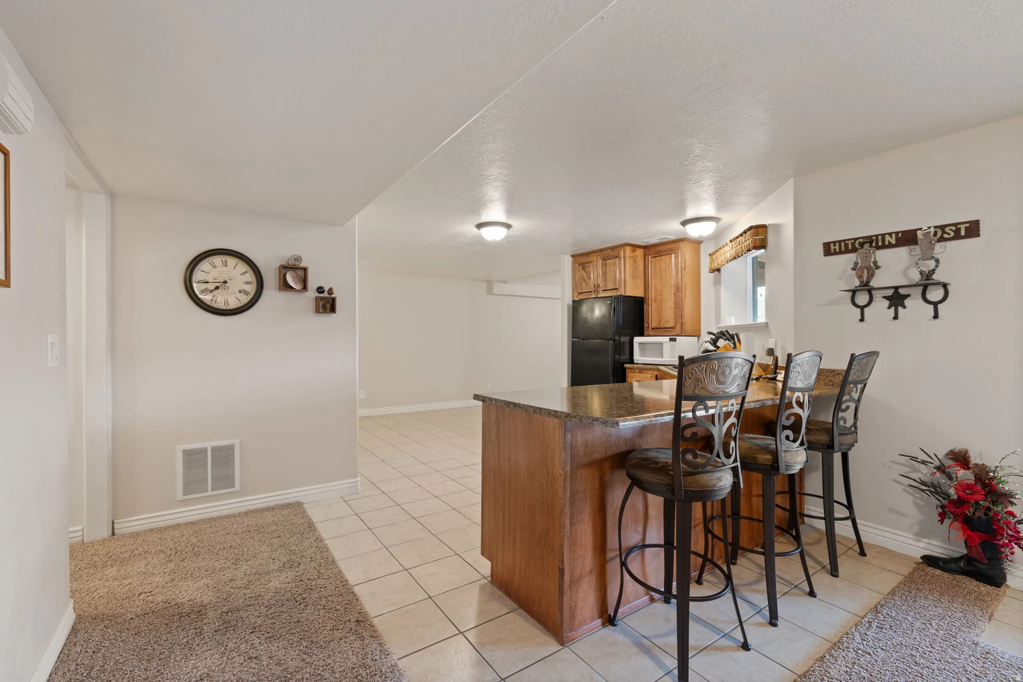Basement Kitchen featuring wood-finish cabinetry, a black refrigerator, and a built-in microwave