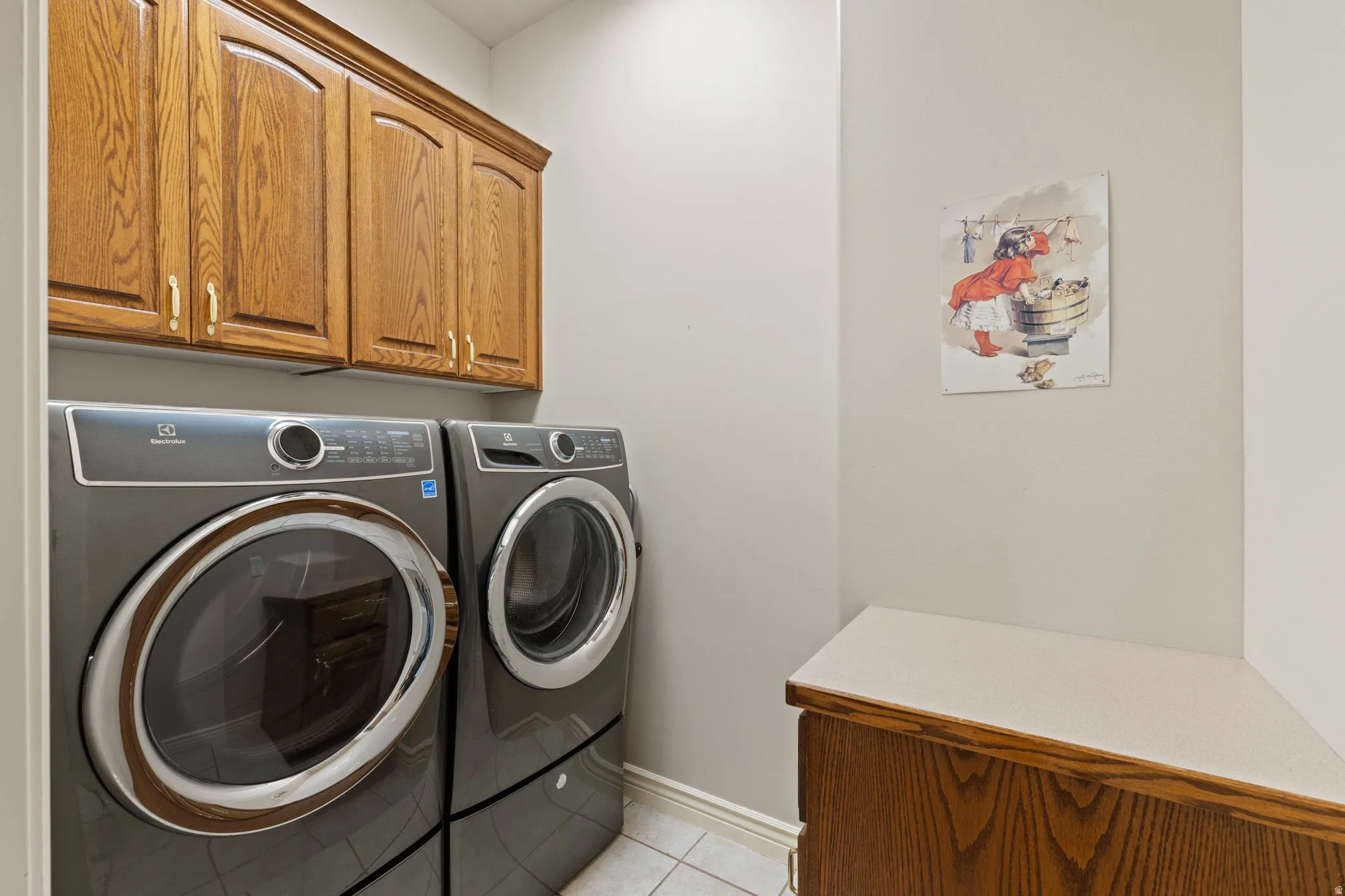 Laundry area featuring wood cabinetry with gold-toned hardware, a white baseboard, and light-toned wall paint