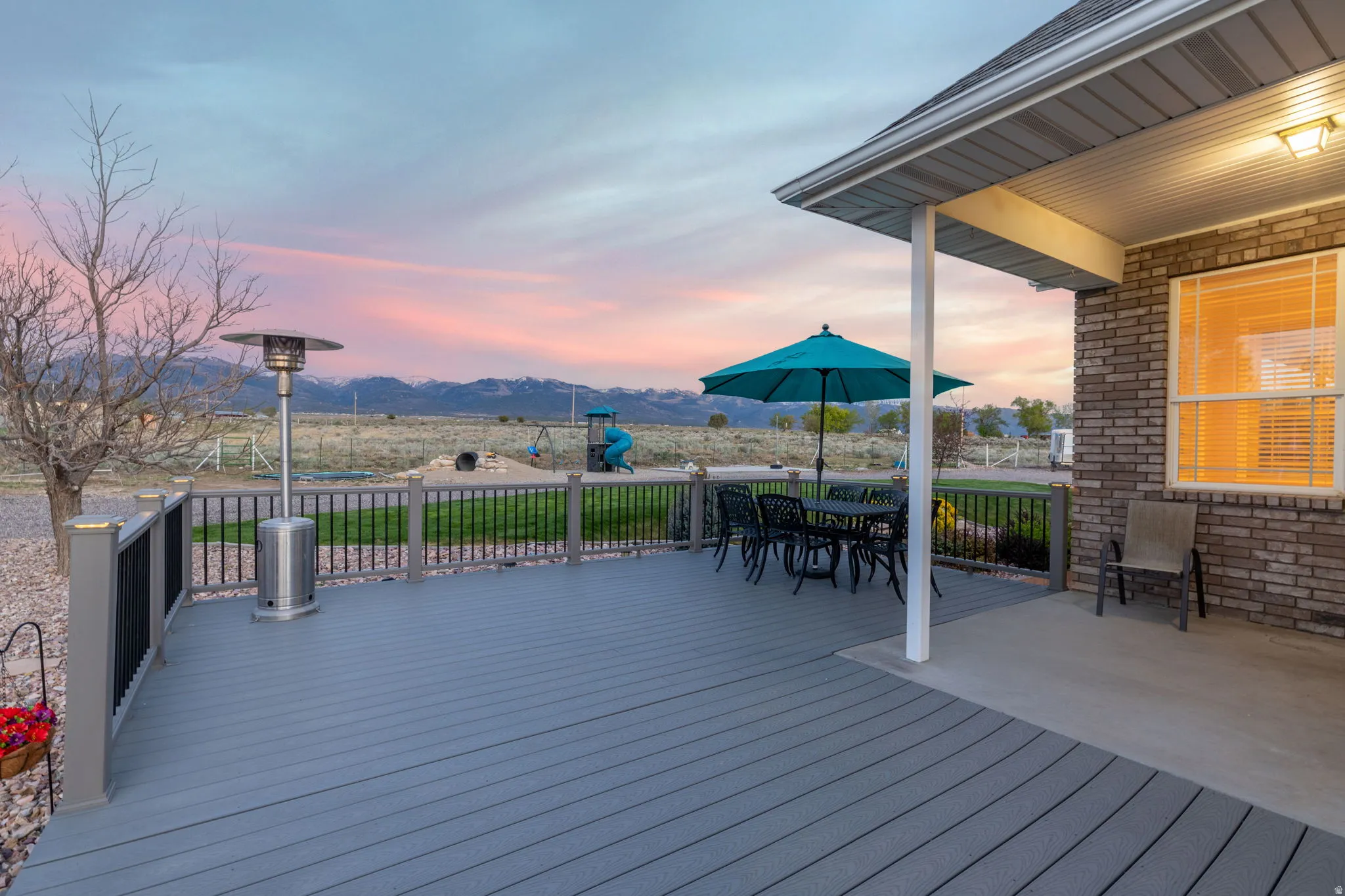 Spacious outdoor deck featuring composite decking, dark railings, and a brick exterior wall