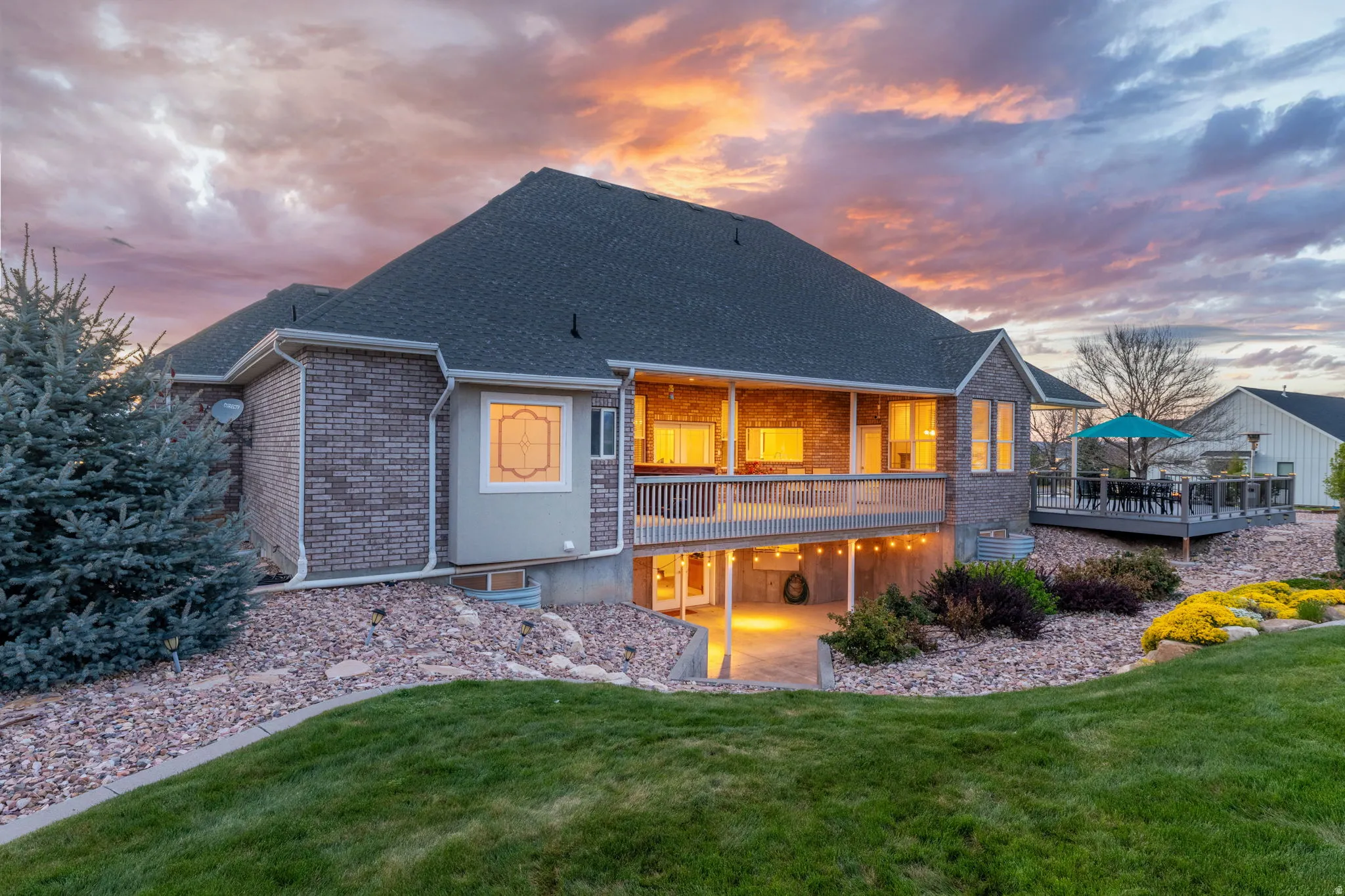 Brick and stucco exterior featuring a multi-level deck, a covered patio, and a manicured lawn