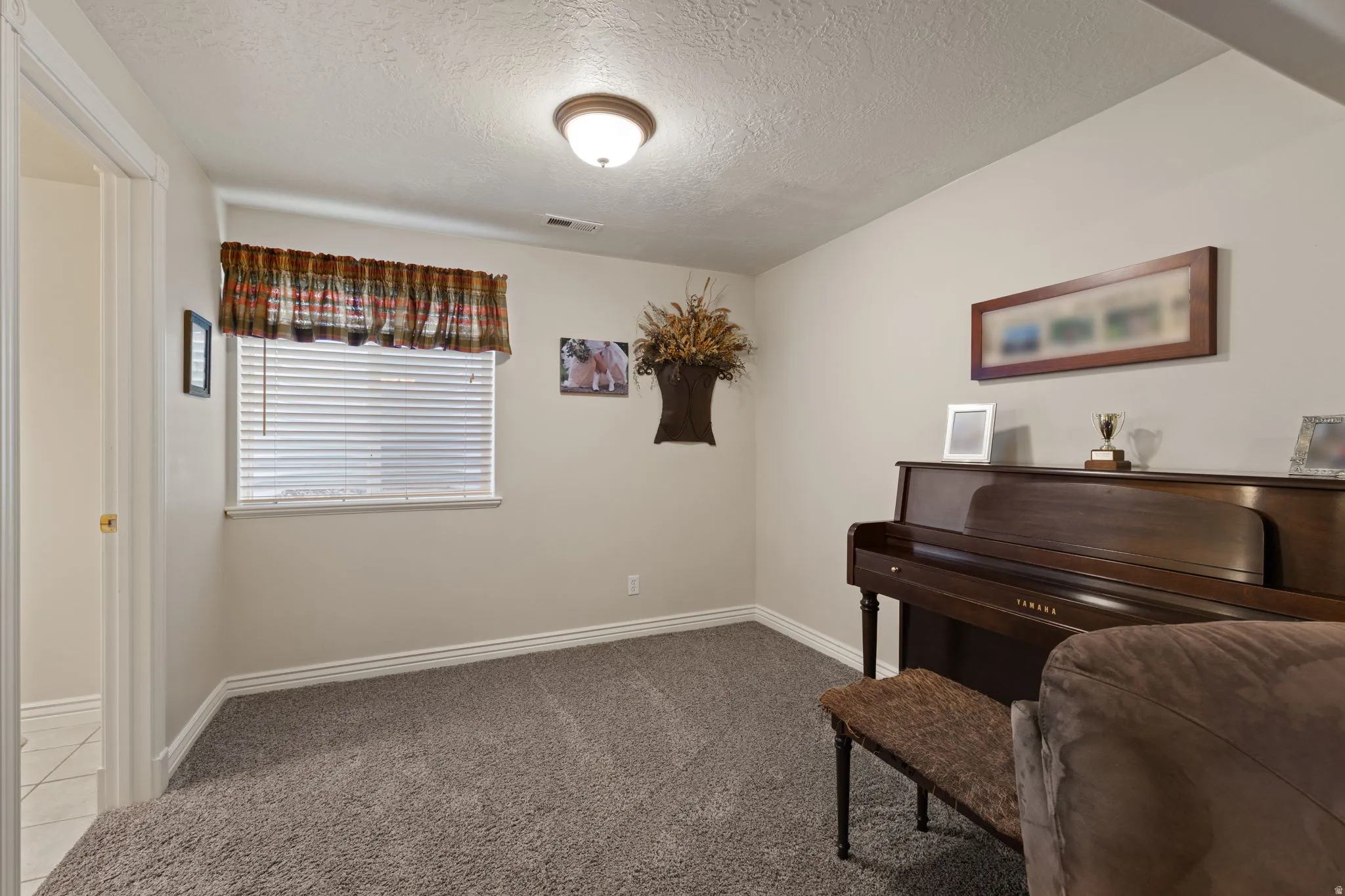 Carpeted room featuring light beige walls and a single window with horizontal blinds