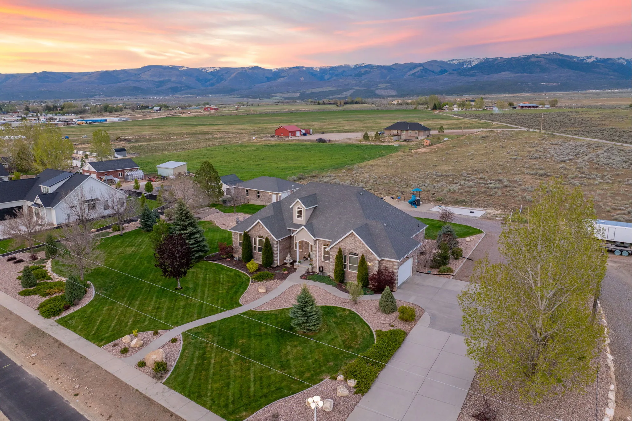 Stone and brick facade residence featuring an attached two-car garage, established landscaping, a paved driveway, and mountain scenery