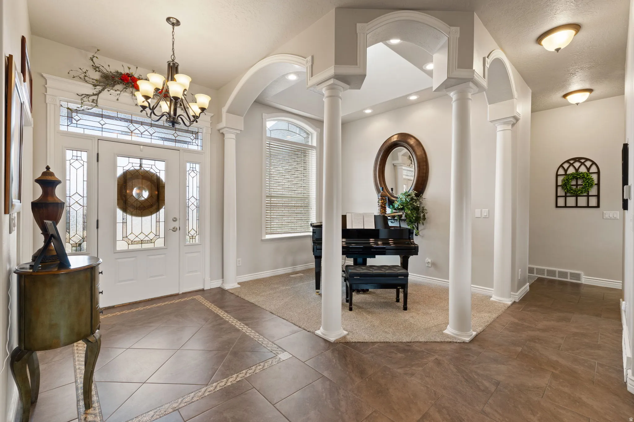 Entryway featuring a decorative front-door entrance with sidelights and transom window, a chandelier, and tile flooring with an accent border
