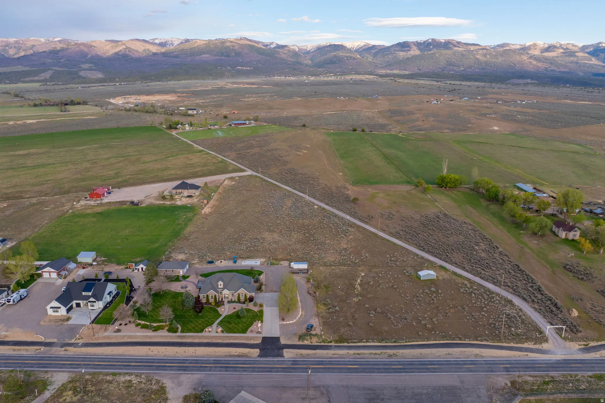 Expansive aerial capturing multiple properties, agricultural fields, and distant mountain ranges