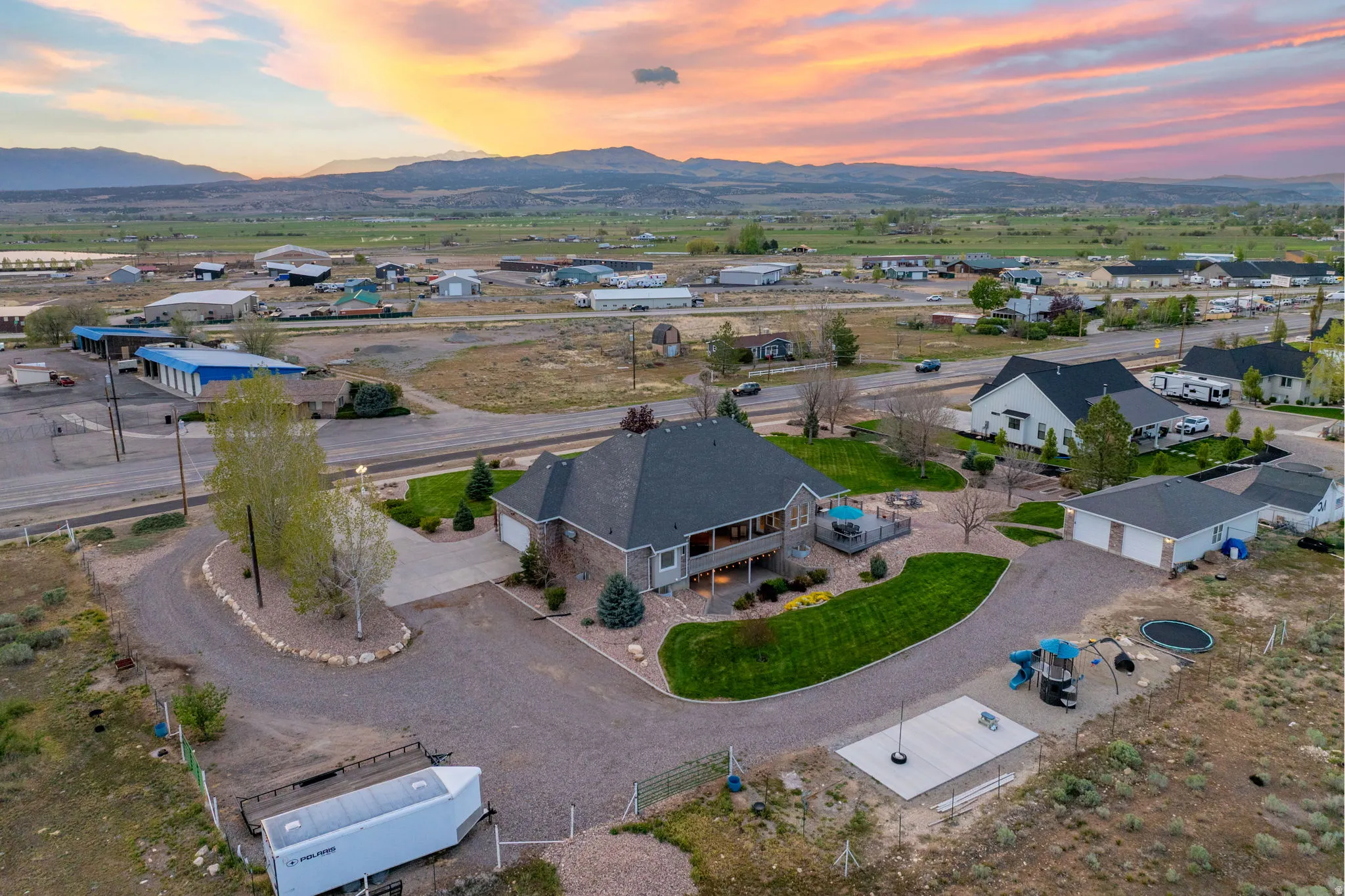 Large property featuring a sprawling gravel driveway, a detached garage, and a spacious rear deck with outdoor seating