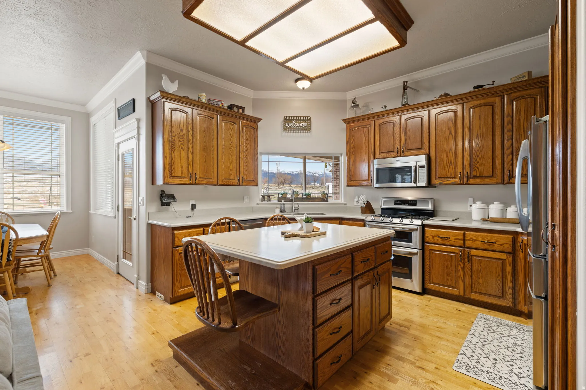 Kitchen featuring wood-finish cabinetry, light-toned countertops, and stainless steel appliances