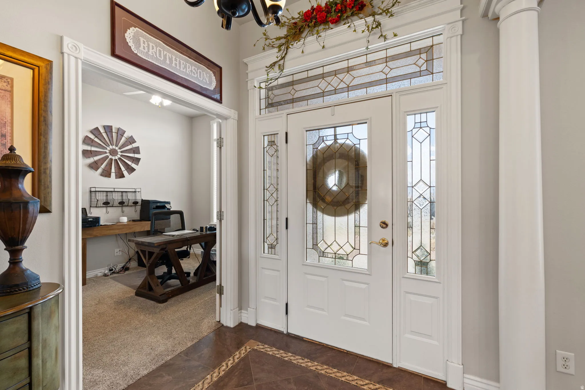 Entryway featuring a white door with decorative glass panels, an arched transom window with geometric patterns, and a sidelight with matching glasswork