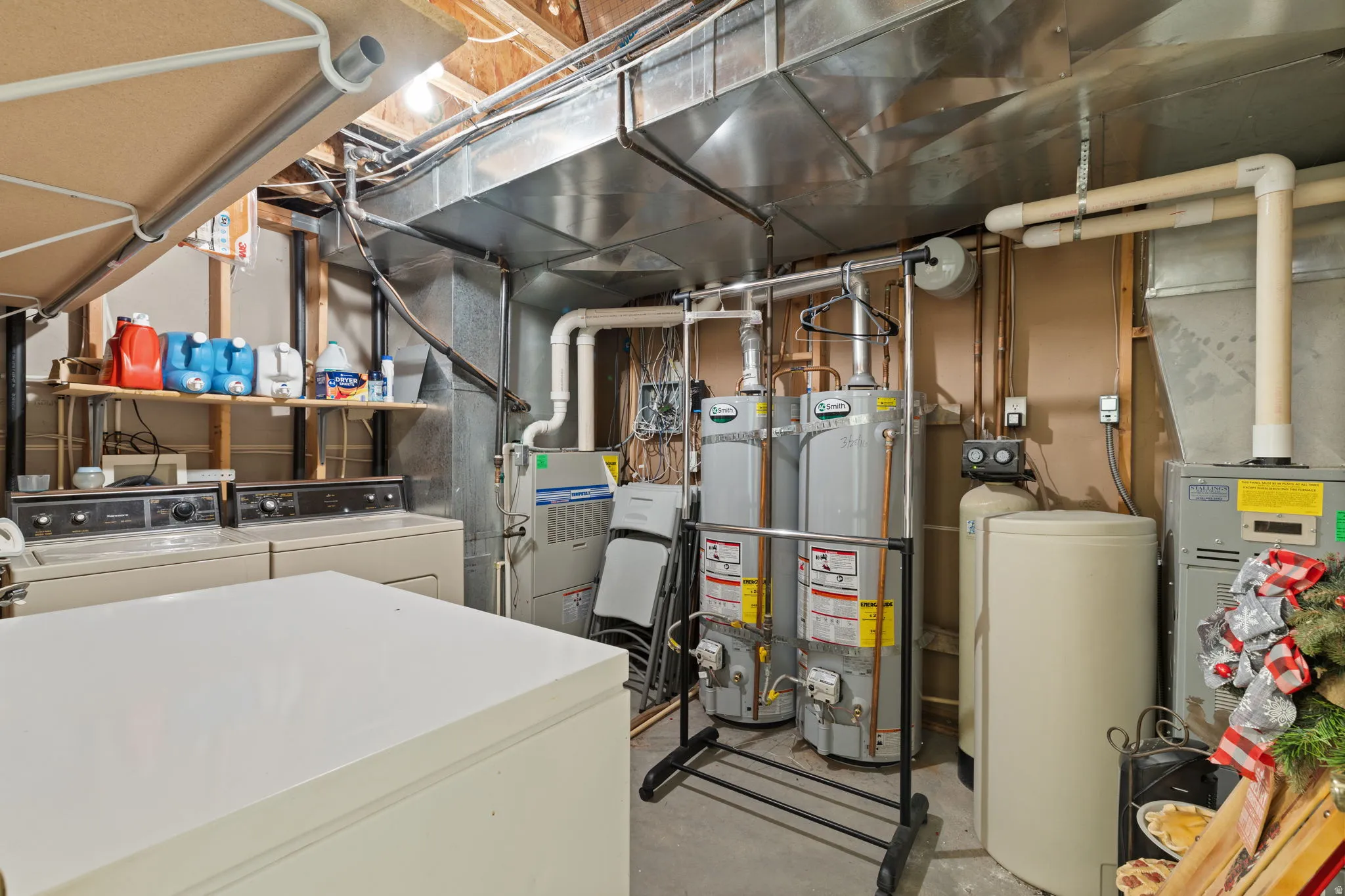 Second laundry in basement and utility room featuring dual water heaters, a water filtration system, and exposed ductwork