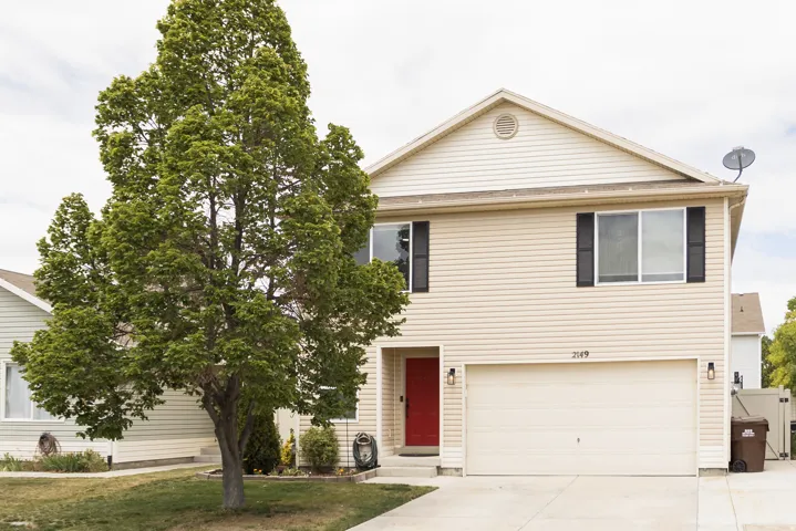 Two-story residence featuring light-colored siding and a contrasting red entry door