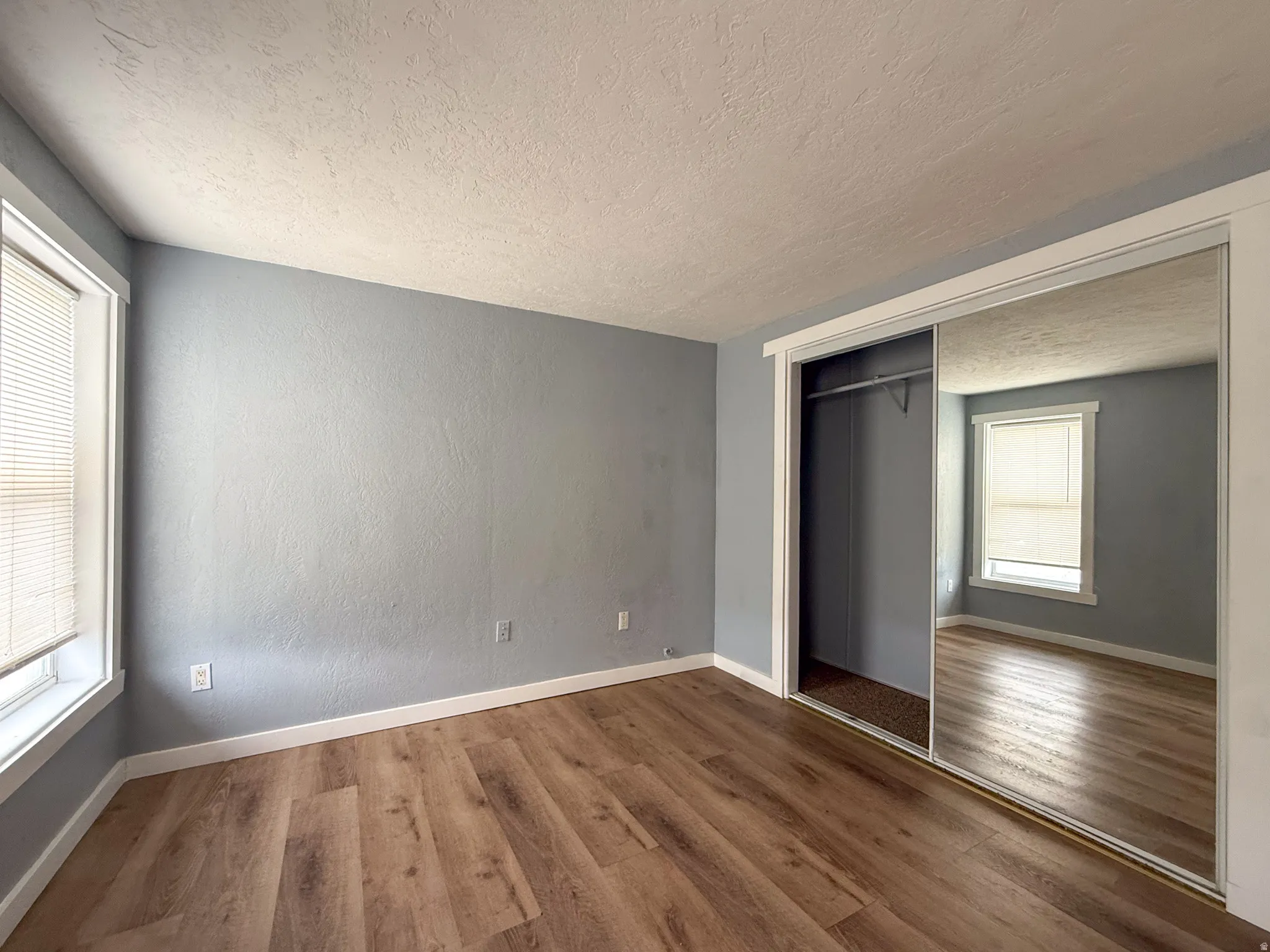 Room featuring wood-finish flooring, light blue walls, and white trim
