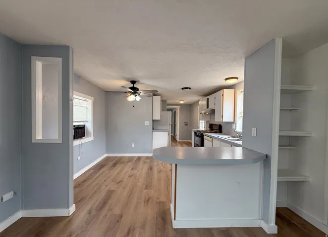 Open concept living area featuring wood-finish flooring, a ceiling fan, and recessed wall niche