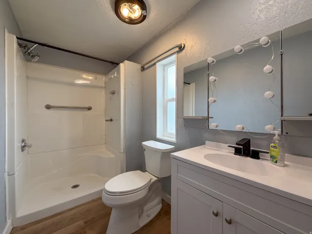 White shower stall with grab bars and a chrome shower head