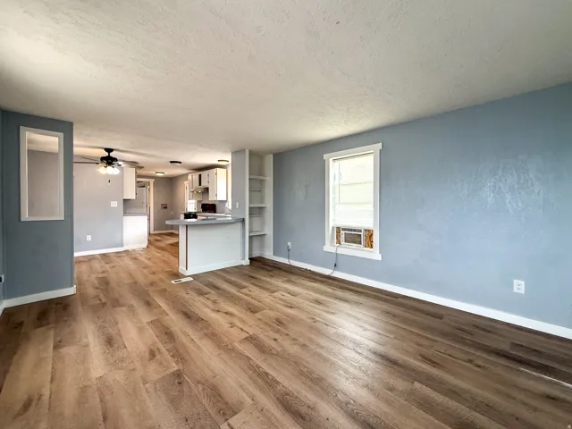 Open-concept living area featuring wood-finish flooring, built-in shelving, and a breakfast bar