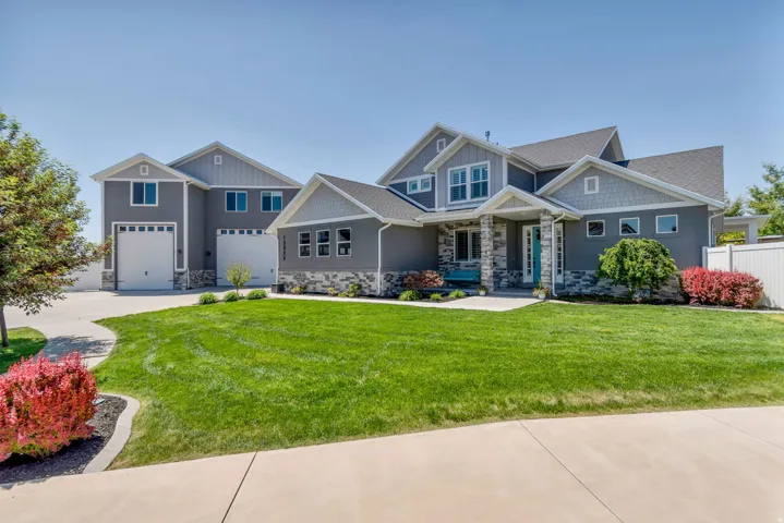 Contemporary gray home with stone veneer accents and a prominent teal entry door