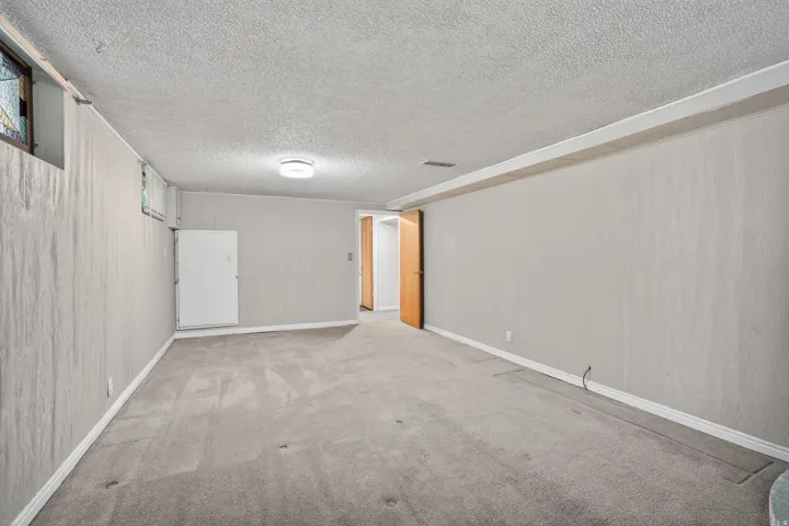 Carpeted room with light gray walls, white baseboards, and a textured ceiling