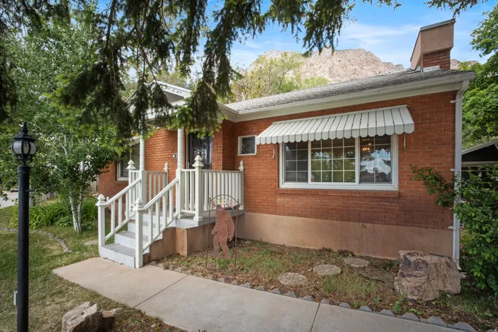 Brick exterior featuring a white aluminum awning and a front porch with white railings