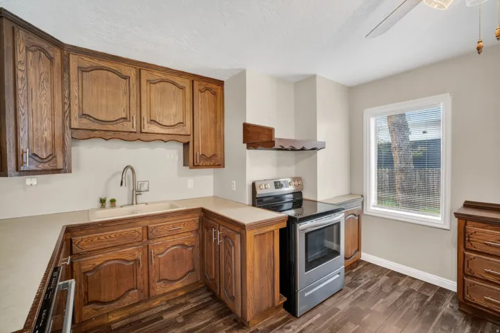 Kitchen featuring wood-finish cabinetry, solid surface countertops, a stainless steel range with ceramic cooktop, and wood-finish flooring