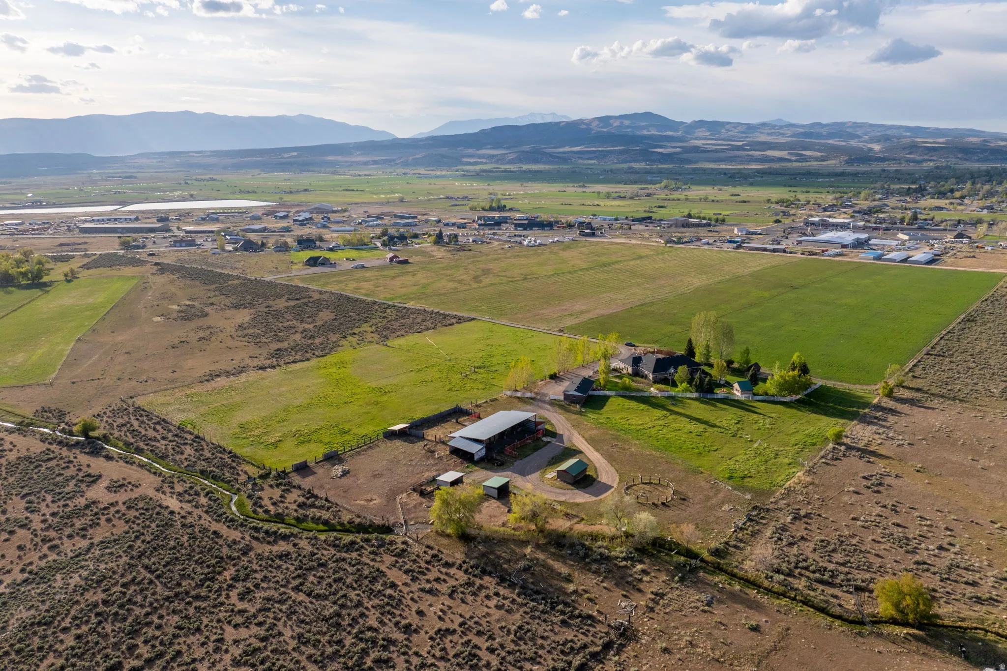 Expansive property featuring multiple agricultural fields, a primary residence with surrounding green space, and several outbuildings