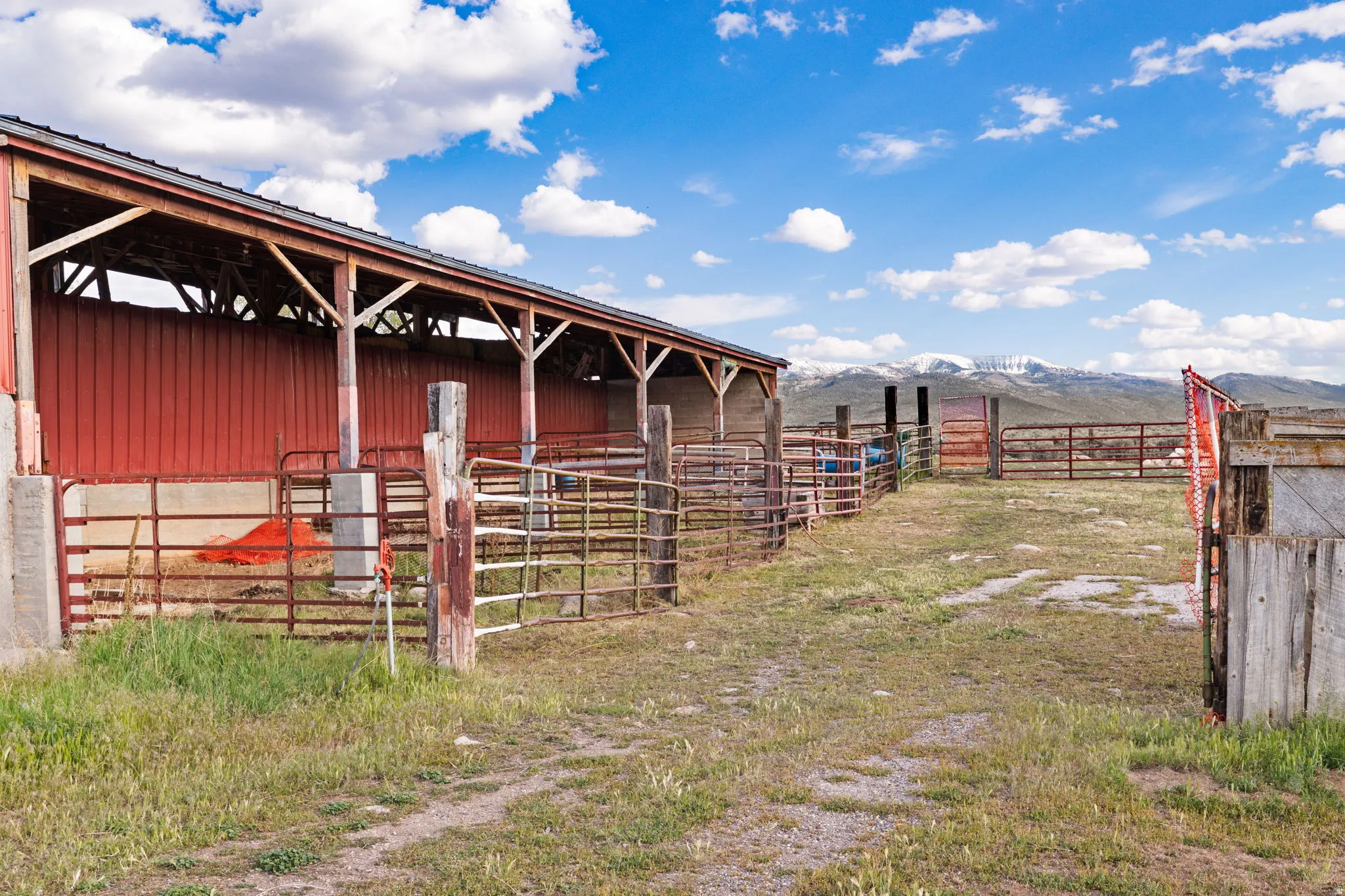 Sheltered barn structure with red metal siding and a dark roof