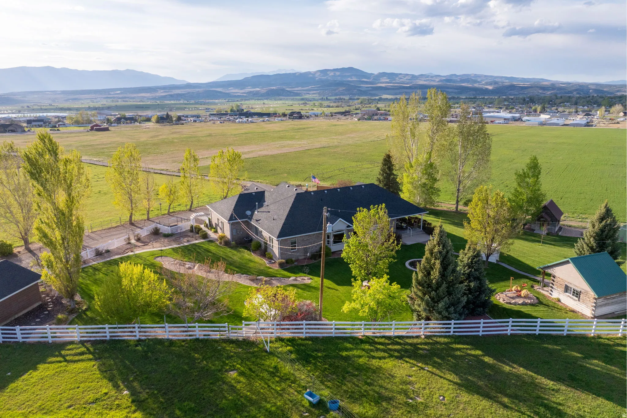 Expansive property featuring a multi-level residence with a dark roof and light-colored siding