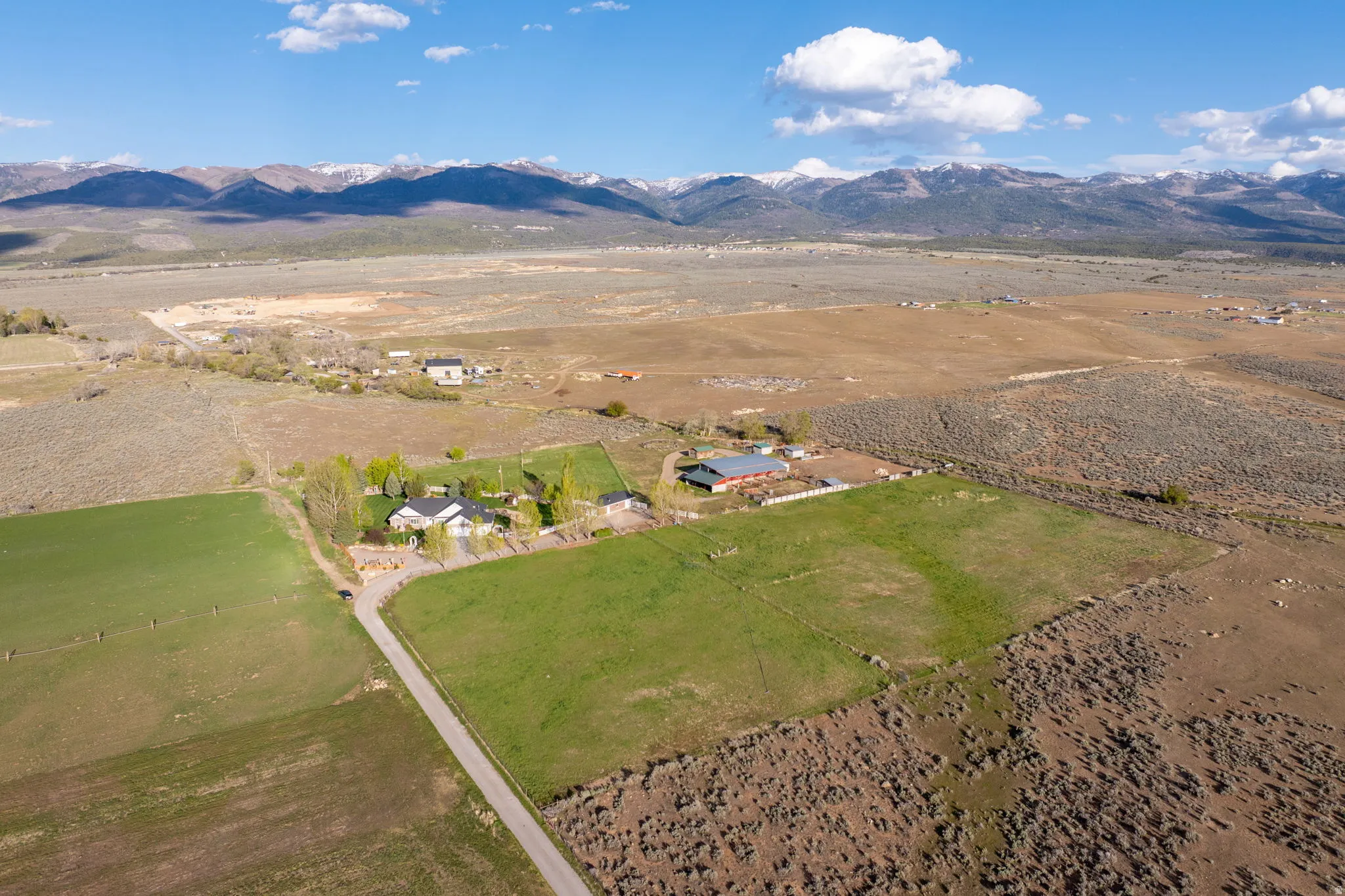 Expansive rural property featuring a main residence, multiple outbuildings, and extensive green pastures