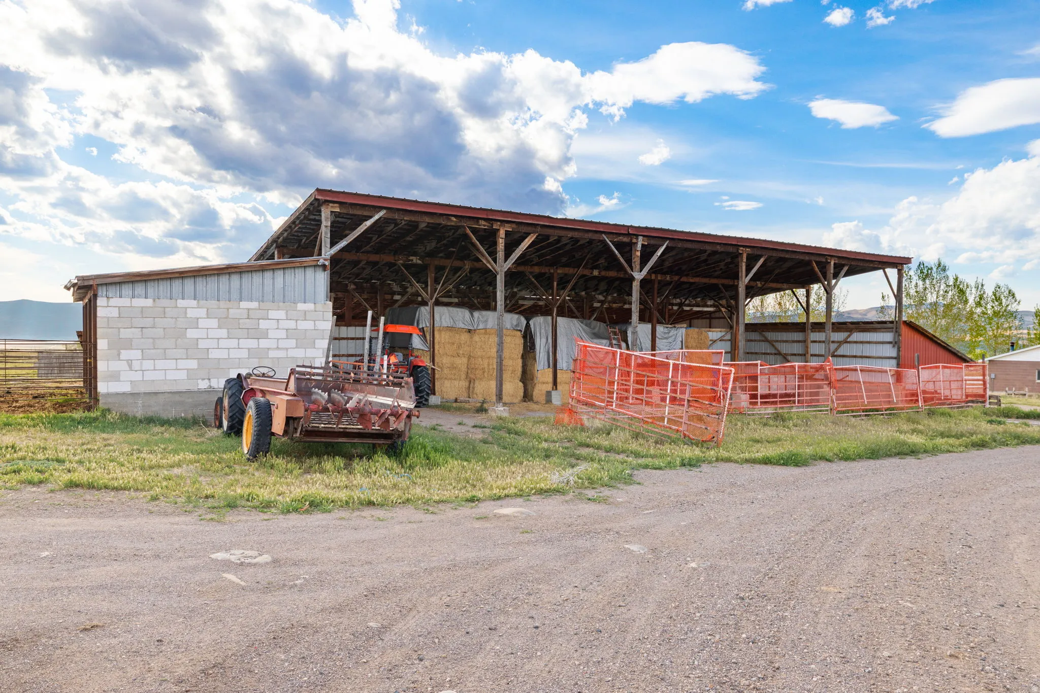 Large open-sided barn structure featuring a metal roof and exposed timber framing