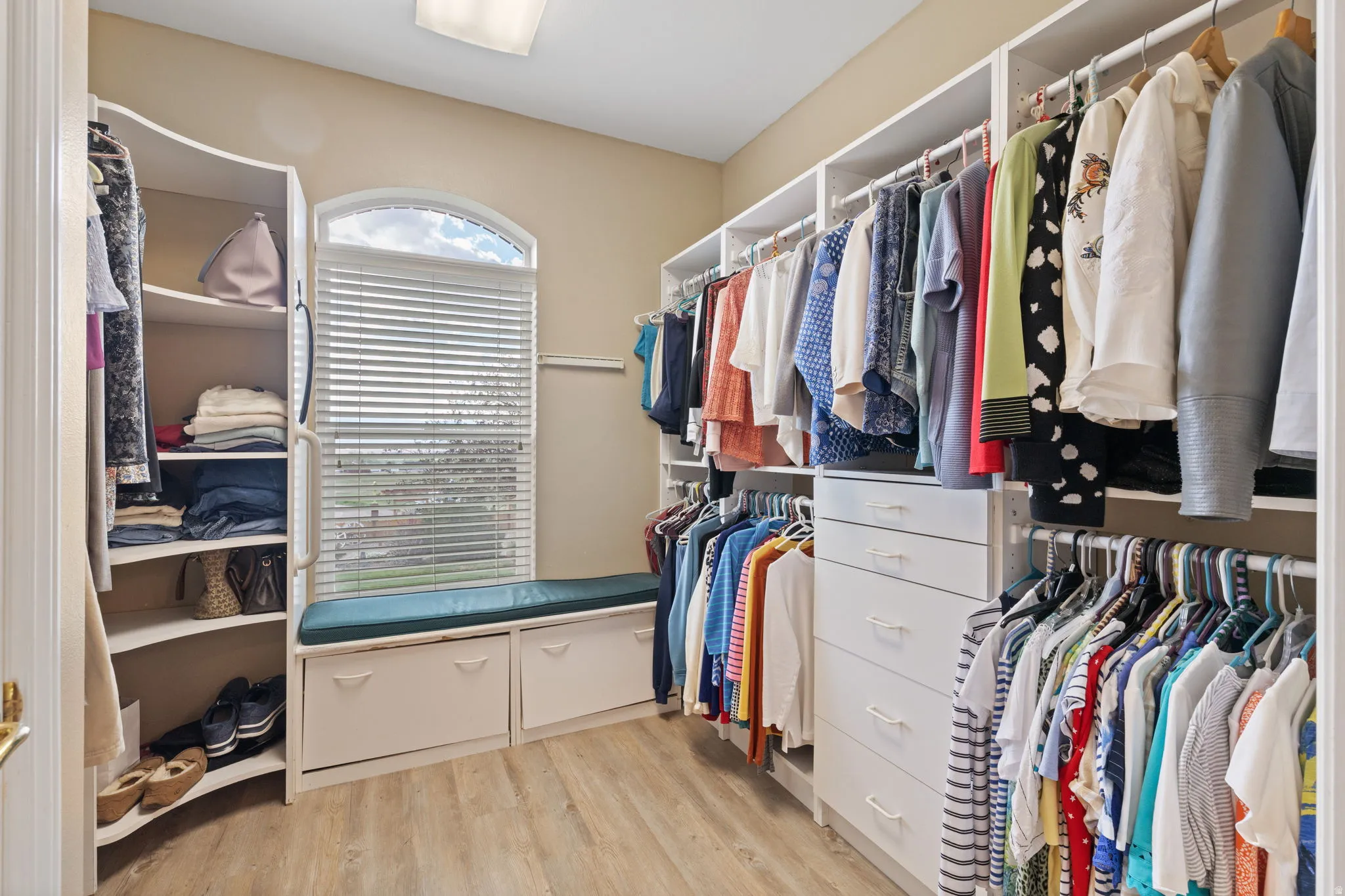 Spacious walk-in closet featuring extensive built-in shelving, hanging rods, and drawer storage