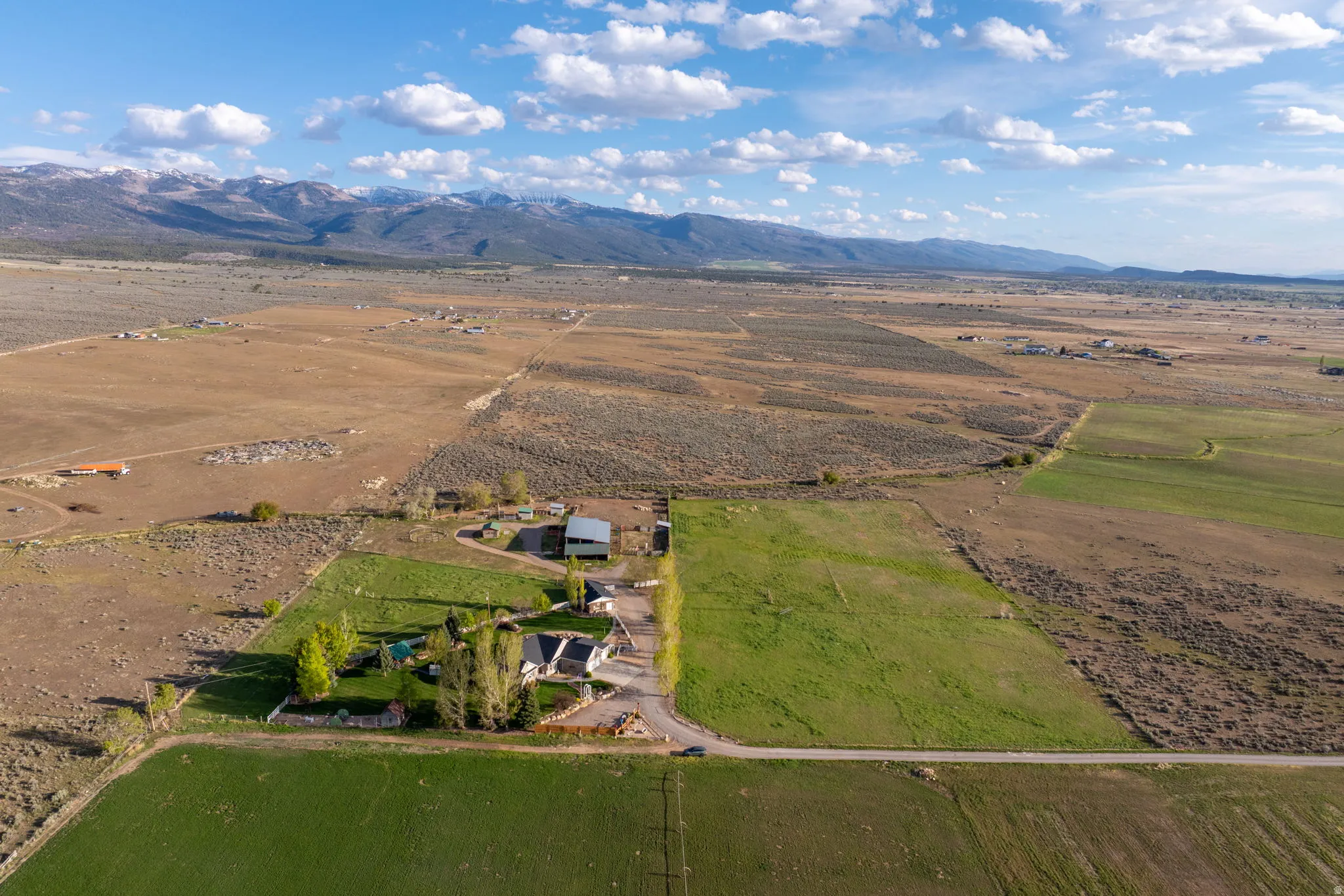 Expansive rural property featuring a main residence, an additional outbuilding, mature trees, and a substantial green field
