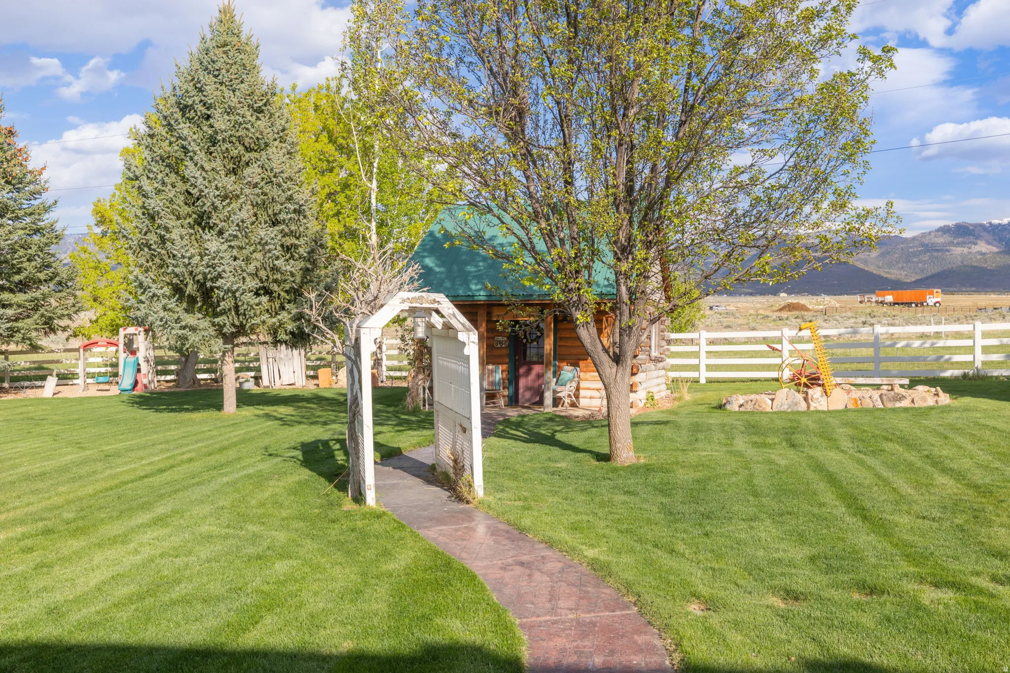 Expansive green lawn with a log cabin structure featuring a green roof