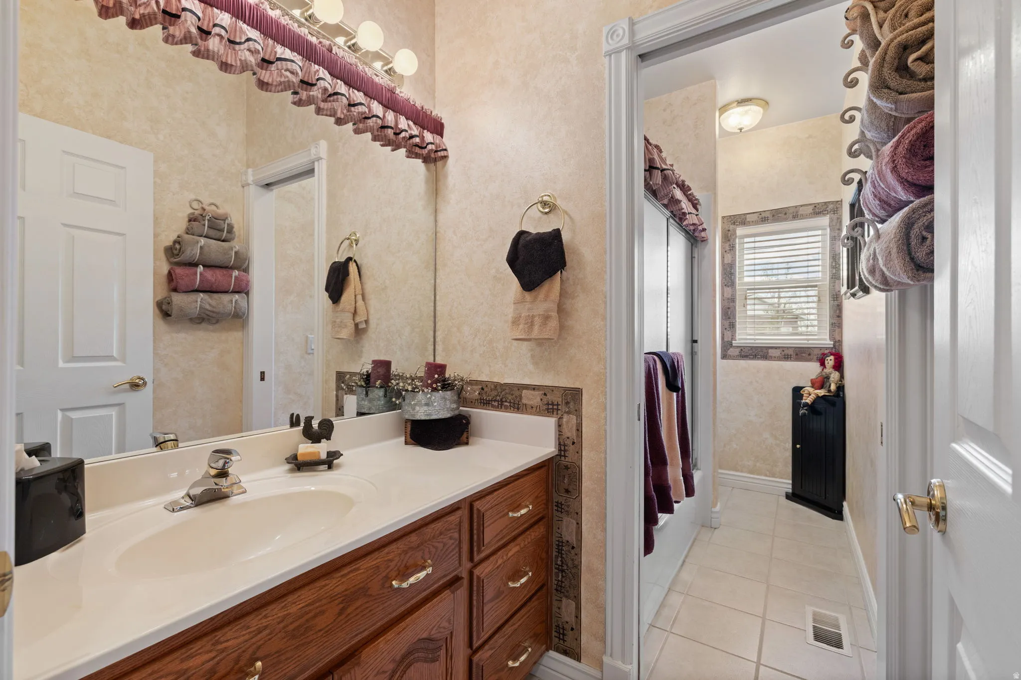 Bathroom vanity with an integrated sink, wood-finish cabinetry, and a light-toned countertop