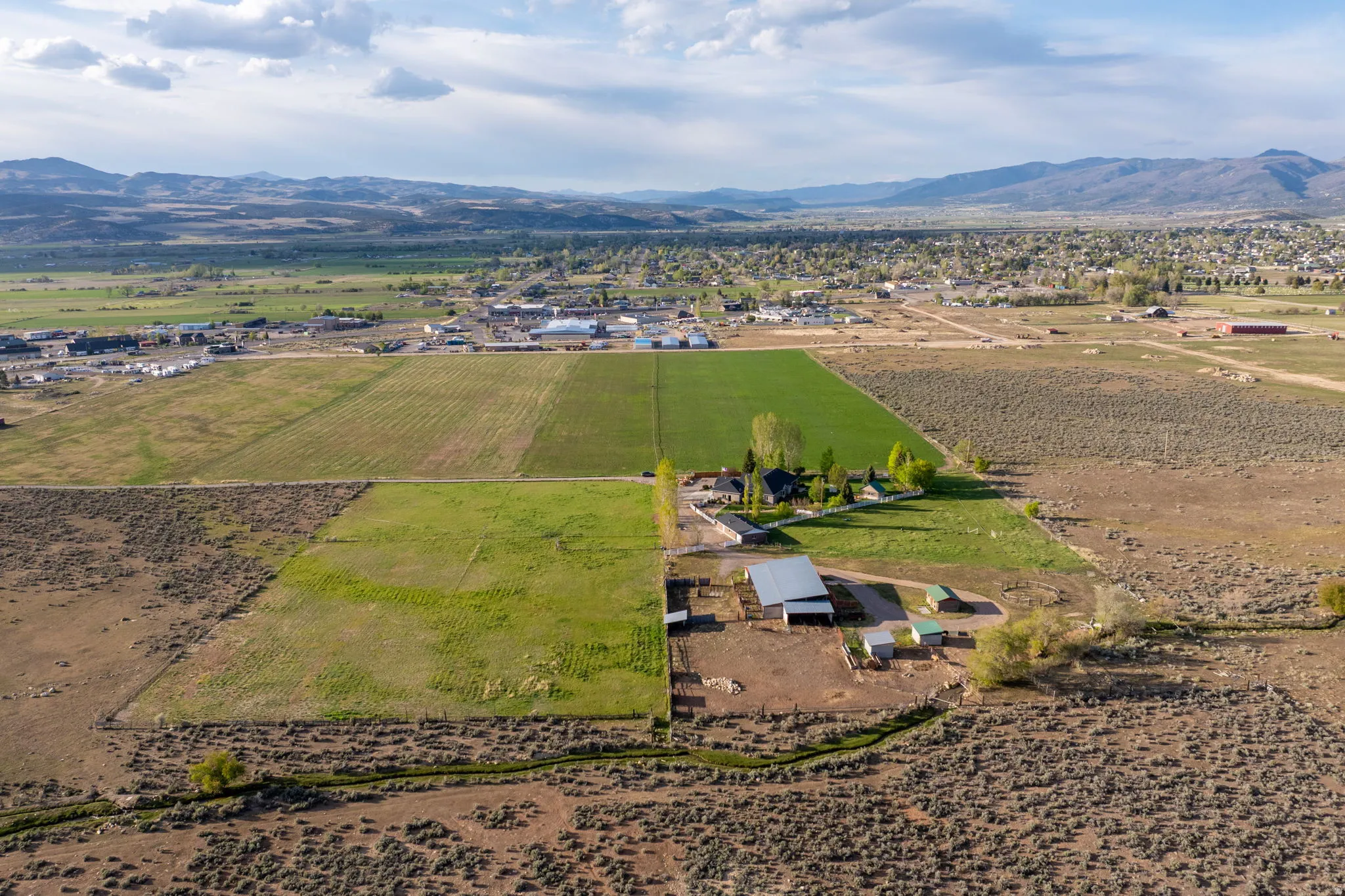 Expansive rural property featuring multiple agricultural fields, a primary residence, and an outbuilding with an attached lean-to