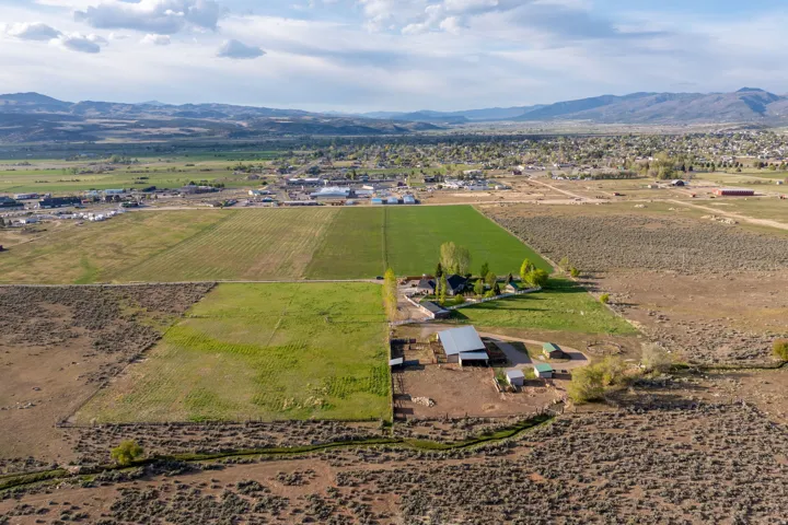 Expansive rural property featuring multiple agricultural fields, a primary residence, and an outbuilding with an attached lean-to
