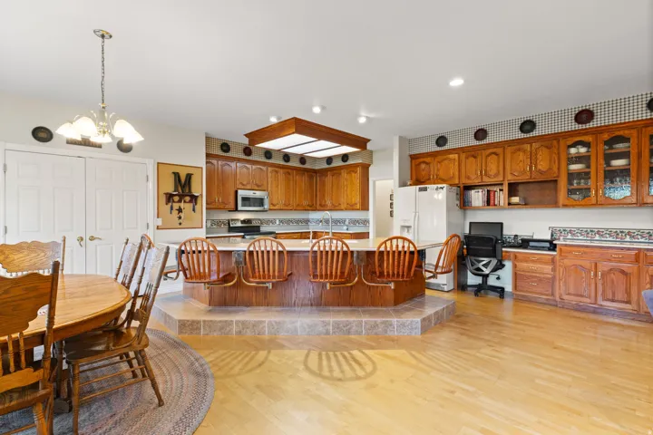 Spacious kitchen featuring a central tiered island with seating, extensive wood cabinetry, and a built-in office nook
