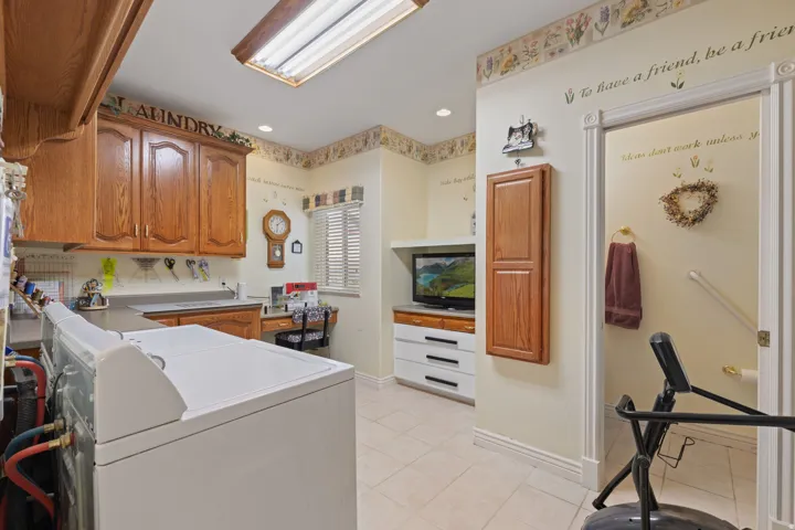 Laundry room featuring wood-finish cabinetry, a built-in countertop, and a window with horizontal blinds