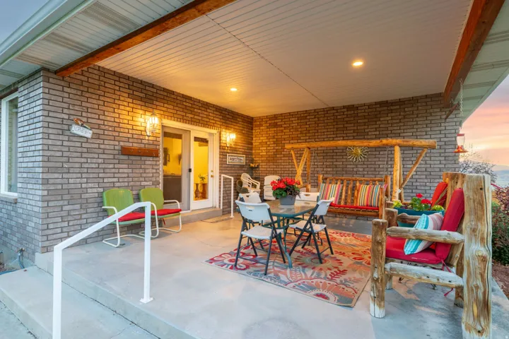 Covered outdoor patio featuring brick siding, concrete flooring, a white railing, recessed lighting, and wall-mounted sconces