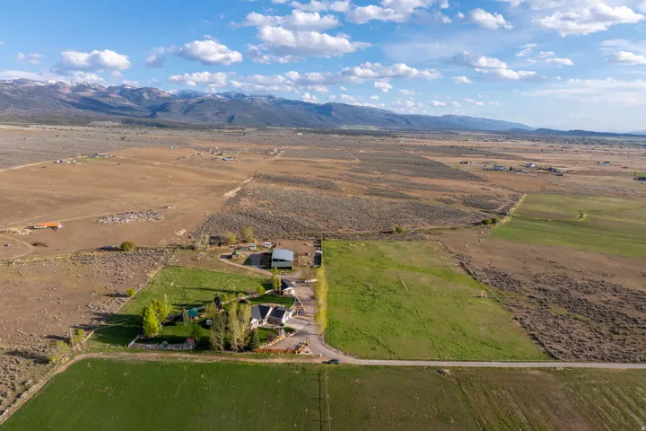 Expansive rural property featuring a main residence, an additional outbuilding, mature trees, and a substantial green field