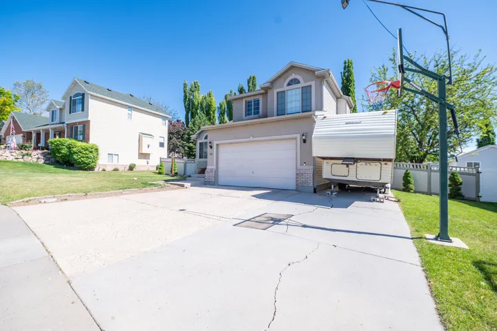 Two-story stucco exterior featuring a two-car garage, a stone veneer accent, and a paved driveway